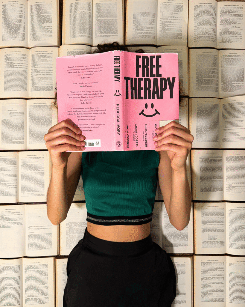 mulher deitada em cima de livros a ler "free therapy".